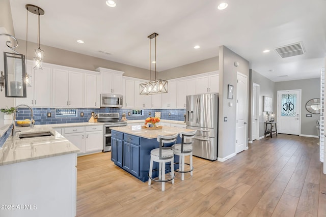 21266 S 213th Pl, Queen Creek, AZ 85142 - kitchen with appliances with stainless steel finishes, blue cabinets, a sink, white cabinetry, and recessed lighting