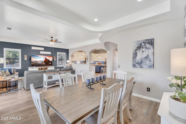 21266 S 213th Pl, Queen Creek, AZ 85142 - dining room featuring arched walkways, light wood finished floors, a raised ceiling, a ceiling fan, and baseboards