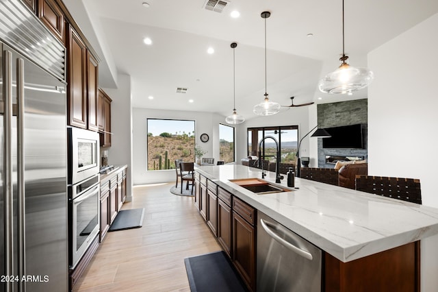 kitchen featuring sink, decorative light fixtures, a large island with sink, a wealth of natural light, and appliances with stainless steel finishes