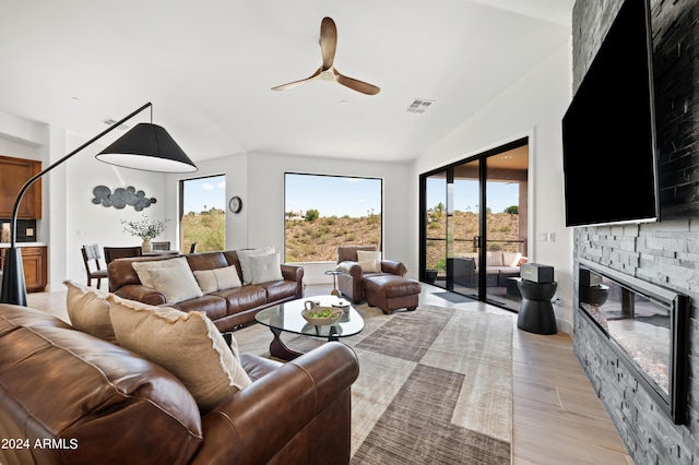 living room featuring ceiling fan, light wood-type flooring, lofted ceiling, and a fireplace