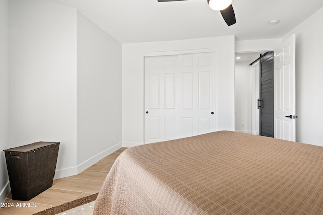 bedroom with ceiling fan, a barn door, and a closet