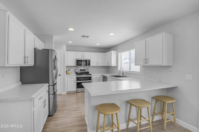 3349 E Flamingo Ct, Gilbert, AZ 85297 - kitchen with stainless steel appliances, a sink, a peninsula, light wood-style flooring, and recessed lighting