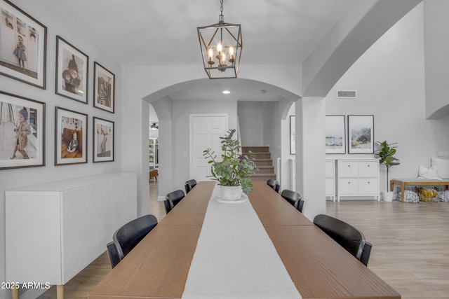3349 E Flamingo Ct, Gilbert, AZ 85297 - dining space with arched walkways, a chandelier, wood finished floors, and stairway