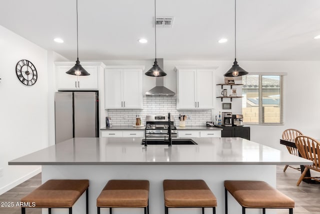 kitchen with stainless steel appliances, white cabinets, and a center island with sink