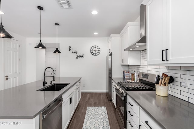 kitchen with pendant lighting, sink, stainless steel appliances, white cabinets, and wall chimney exhaust hood