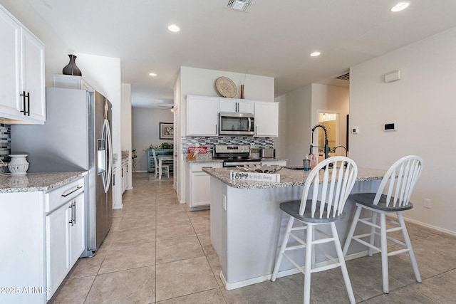 kitchen with white cabinetry, stainless steel appliances, and light stone counters