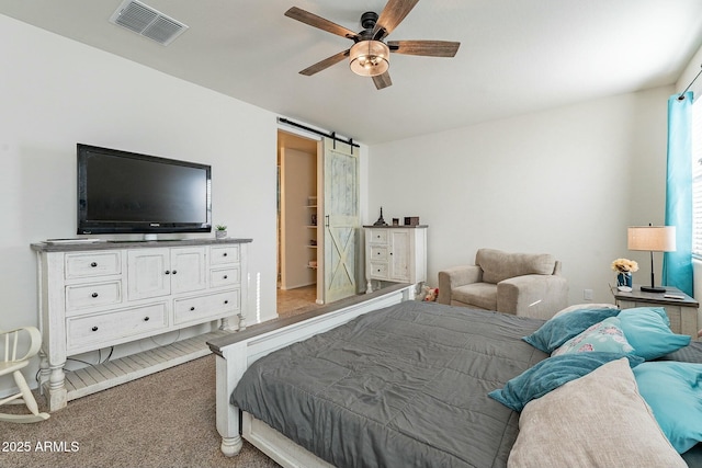 bedroom with carpet, ceiling fan, and a barn door