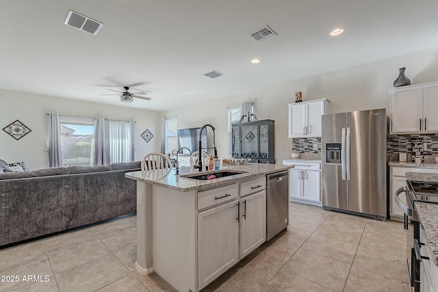 kitchen with white cabinets, sink, an island with sink, and appliances with stainless steel finishes