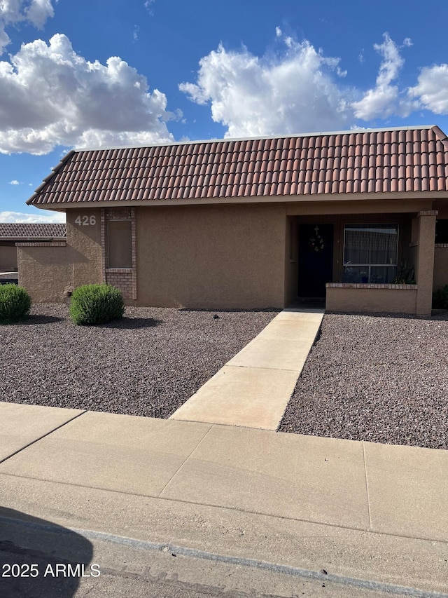 single story home featuring a tiled roof and stucco siding