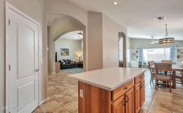 kitchen with light countertops, visible vents, arched walkways, and ceiling fan