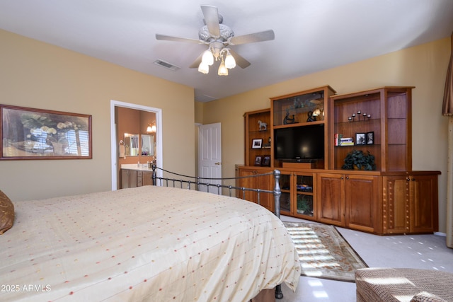 bedroom featuring ceiling fan, ensuite bathroom, and light colored carpet