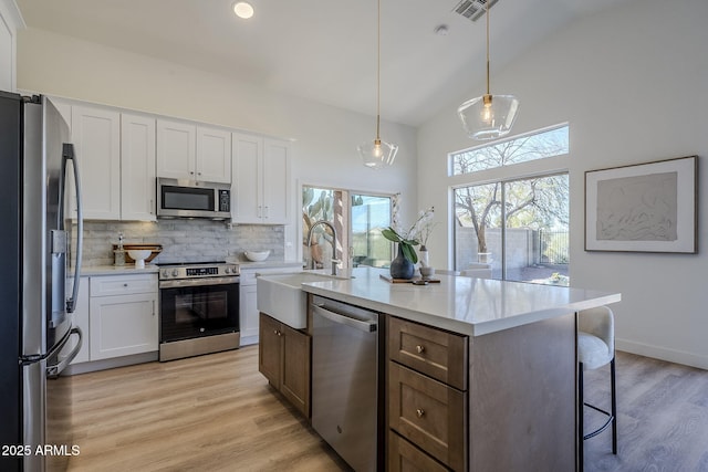 kitchen with visible vents, decorative backsplash, stainless steel appliances, light countertops, and a sink