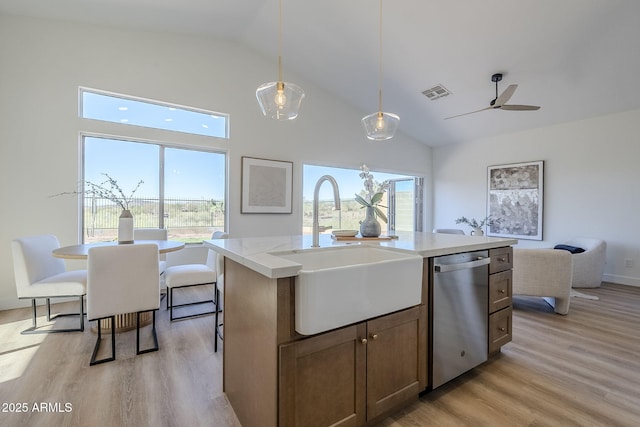 kitchen with a sink, visible vents, light wood-style floors, stainless steel dishwasher, and decorative light fixtures