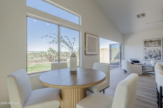 dining room with vaulted ceiling, a wealth of natural light, wood finished floors, and visible vents