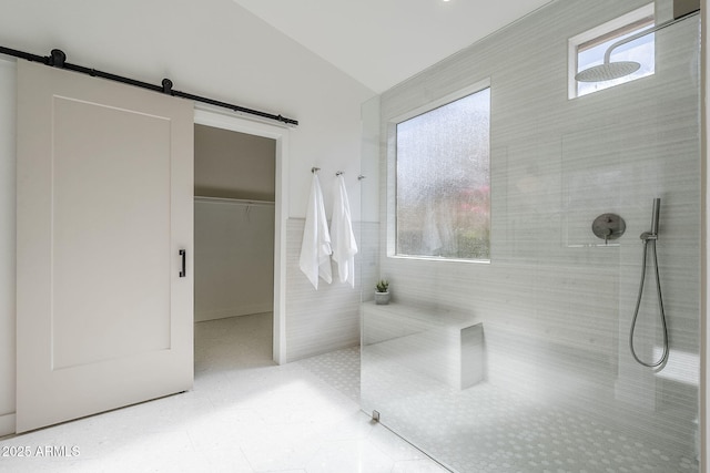 bathroom with lofted ceiling, a spacious closet, a walk in shower, and tile patterned floors