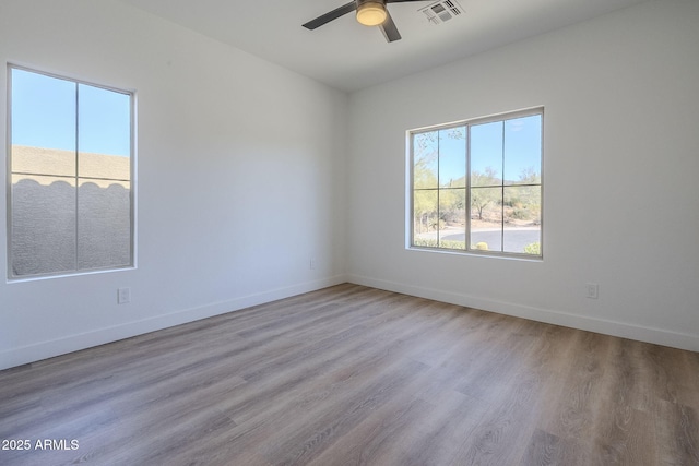 unfurnished room with baseboards, wood finished floors, and a healthy amount of sunlight