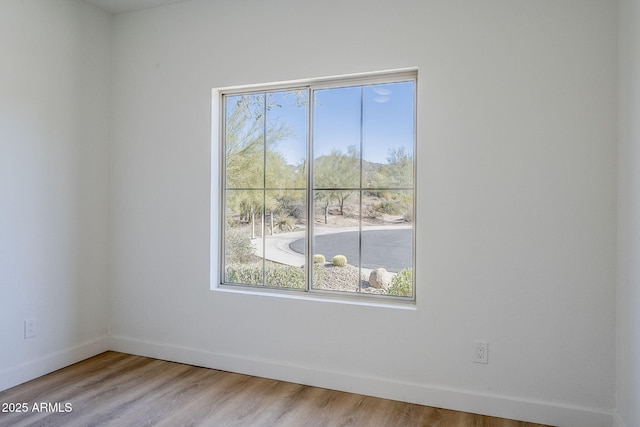 empty room with baseboards, wood finished floors, and a healthy amount of sunlight