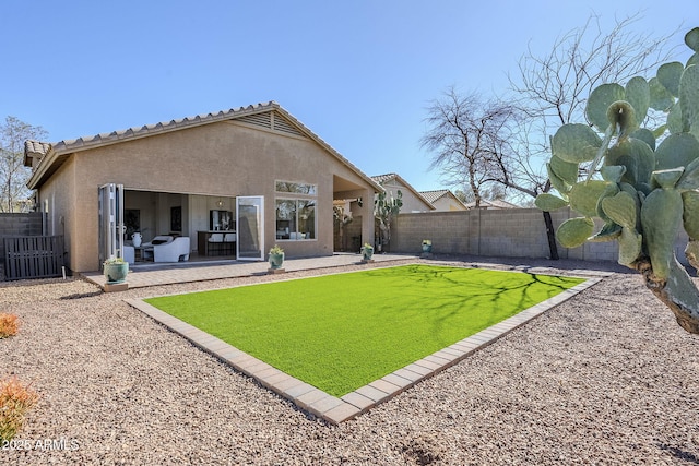 rear view of house featuring a fenced backyard, a tiled roof, a yard, a patio area, and stucco siding