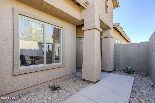 property entrance featuring fence, a patio, and stucco siding