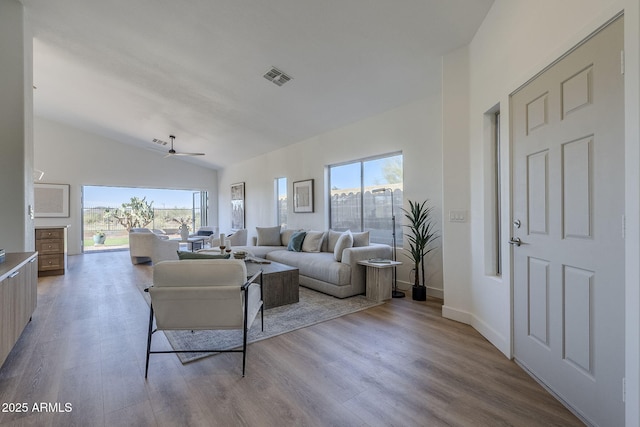 living room with plenty of natural light, light wood-style flooring, visible vents, and vaulted ceiling