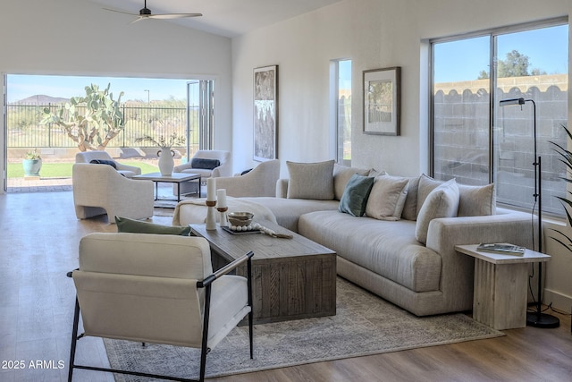 living area with a ceiling fan, vaulted ceiling, and wood finished floors