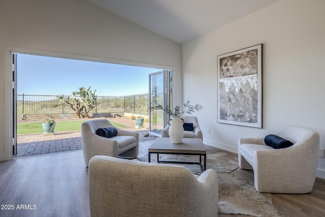 living area with baseboards, vaulted ceiling, and wood finished floors