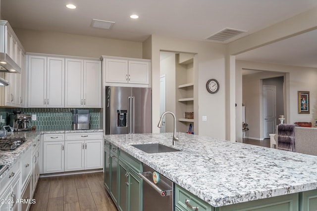 kitchen with a kitchen island with sink, high end refrigerator, green cabinets, sink, and white cabinetry