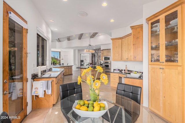 kitchen featuring kitchen peninsula, appliances with stainless steel finishes, light brown cabinetry, sink, and pendant lighting