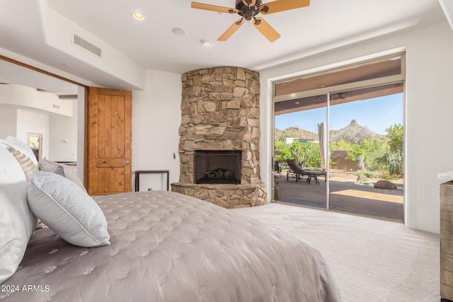 bedroom featuring carpet floors, access to outside, a stone fireplace, and ceiling fan