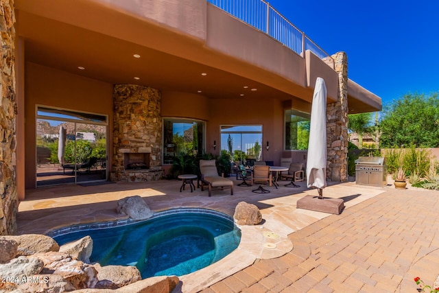 view of swimming pool with a patio area, an outdoor stone fireplace, and a hot tub