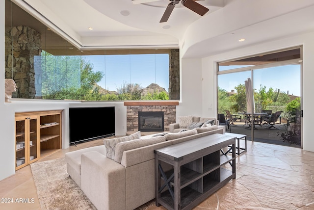 living room featuring a stone fireplace and ceiling fan