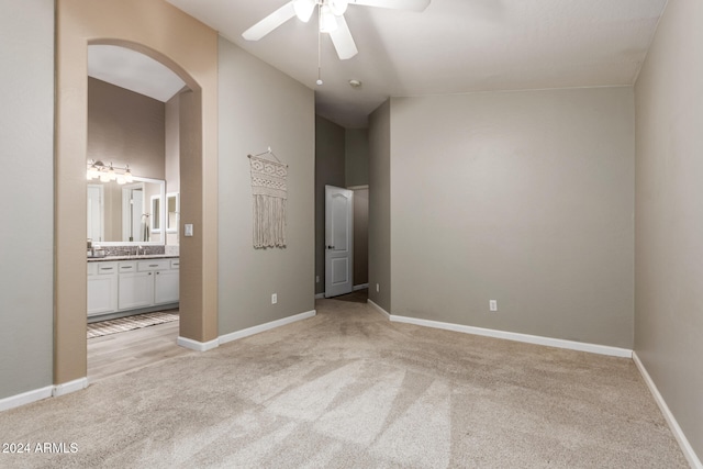 unfurnished room with ceiling fan, sink, and light carpet