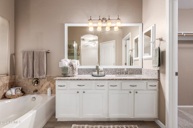 bathroom with hardwood / wood-style floors, vanity, ceiling fan, and a bath