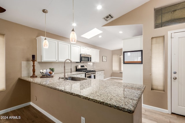 kitchen with kitchen peninsula, appliances with stainless steel finishes, light stone countertops, pendant lighting, and white cabinetry