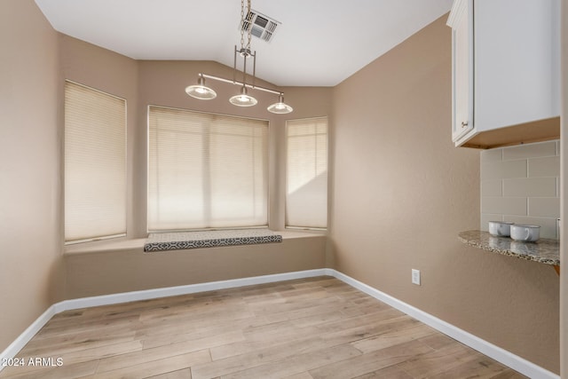 unfurnished dining area with lofted ceiling and light wood-type flooring