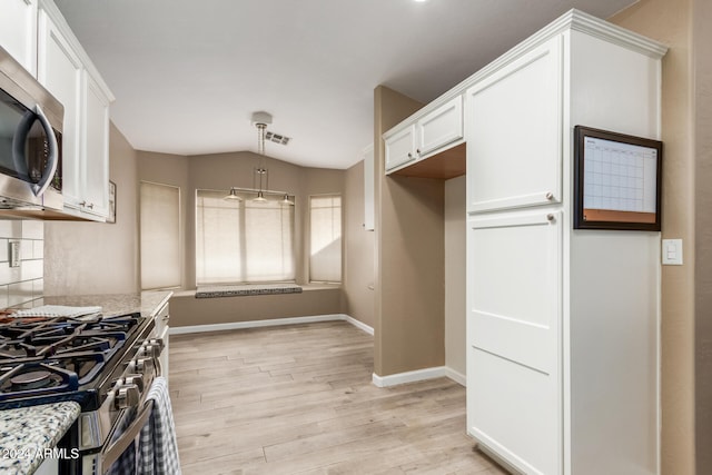 kitchen featuring light stone countertops, white cabinets, light hardwood / wood-style floors, and appliances with stainless steel finishes