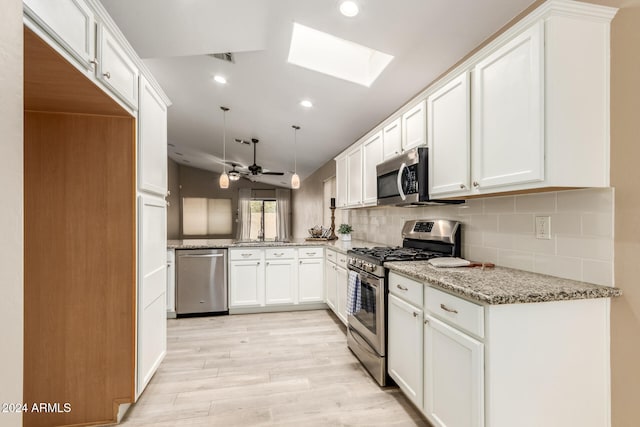 kitchen with light stone countertops, appliances with stainless steel finishes, light wood-type flooring, a skylight, and white cabinets