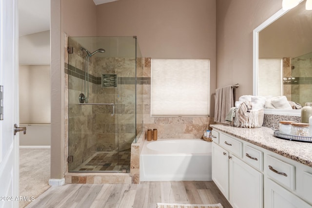 bathroom with hardwood / wood-style floors, vanity, shower with separate bathtub, and vaulted ceiling