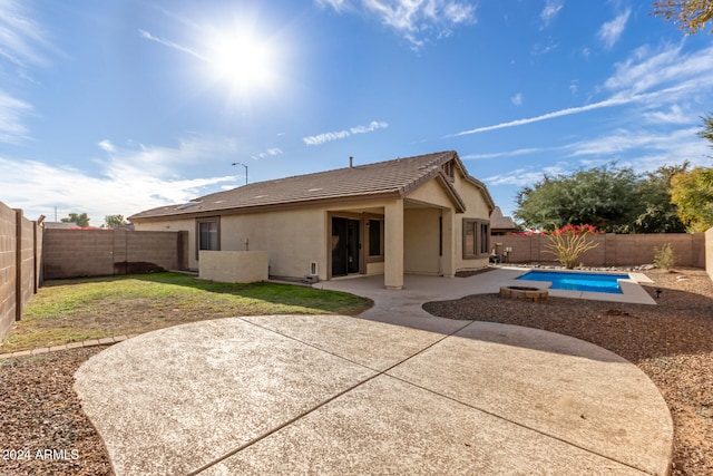 rear view of house with a fenced in pool and a patio area