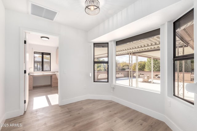 unfurnished room with a chandelier and light hardwood / wood-style flooring