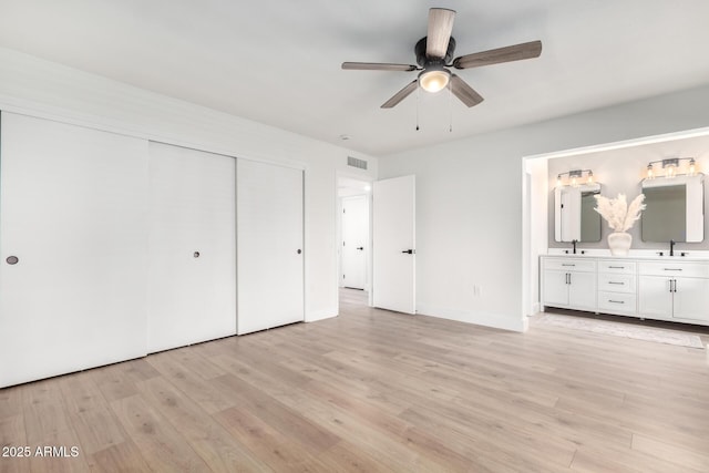 unfurnished bedroom featuring ceiling fan, light hardwood / wood-style floors, ensuite bathroom, and a closet