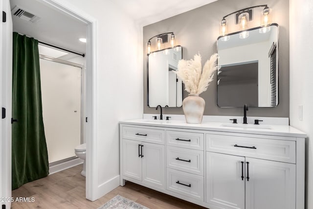 bathroom with vanity, toilet, wood-type flooring, and an enclosed shower