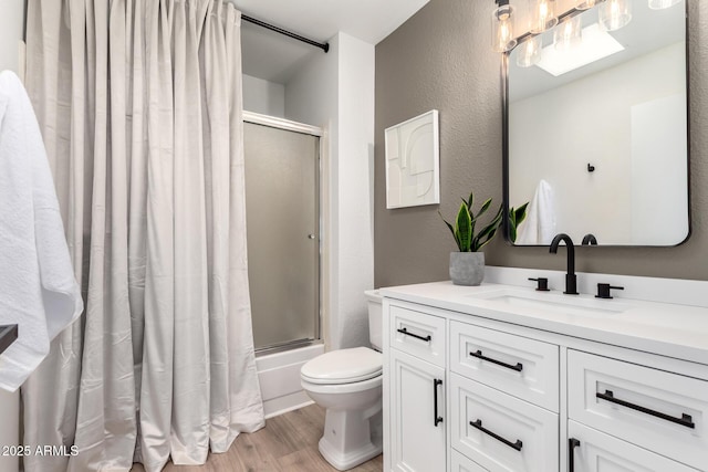 full bathroom with hardwood / wood-style floors, shower / bath combination with glass door, vanity, and toilet