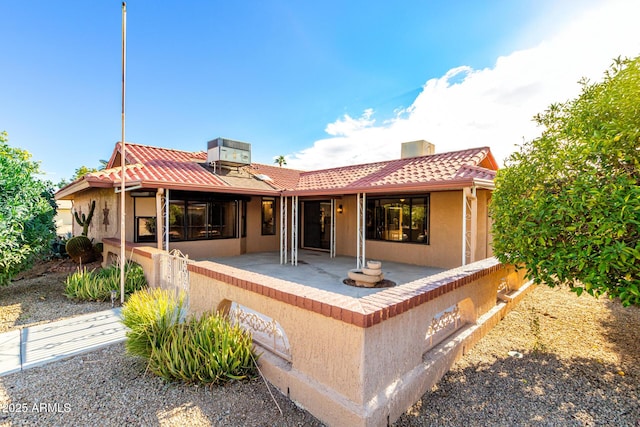 rear view of house with central AC unit and a patio