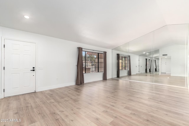 unfurnished living room with vaulted ceiling and light hardwood / wood-style flooring