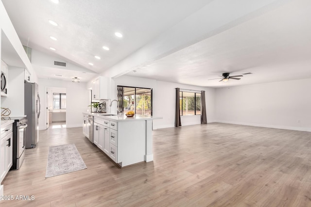 kitchen featuring ceiling fan, lofted ceiling, sink, white cabinetry, and appliances with stainless steel finishes