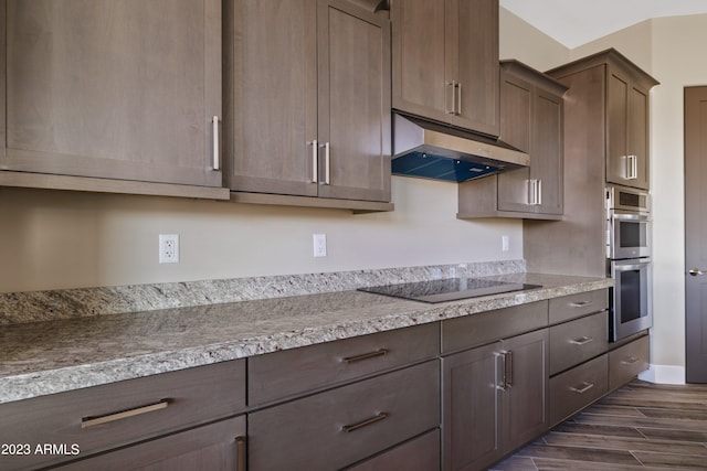 kitchen with dark hardwood / wood-style floors, light stone counters, stainless steel double oven, and black electric stovetop