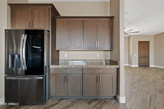 kitchen featuring hardwood / wood-style flooring, light stone counters, stainless steel refrigerator with ice dispenser, and ceiling fan