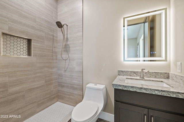 bathroom with tiled shower, vanity, and toilet