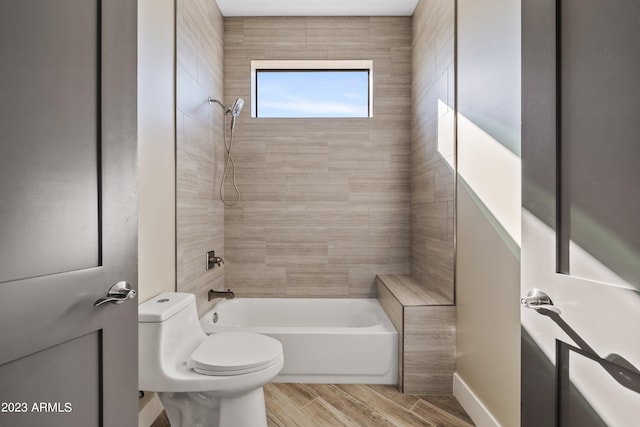 bathroom with toilet and tiled shower / bath